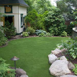 Artificial grass in backyard lawn surrounded by foliage