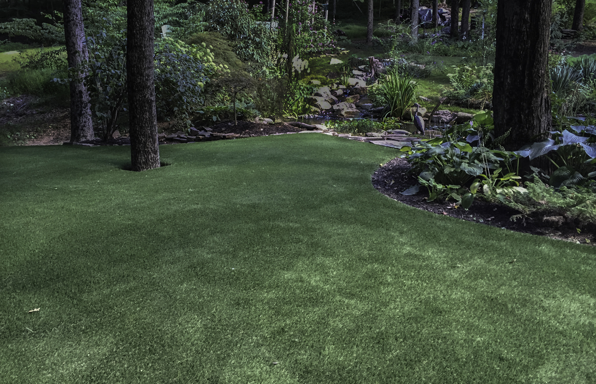 Artificial grass lawn in the middle of a lush forest in NJ