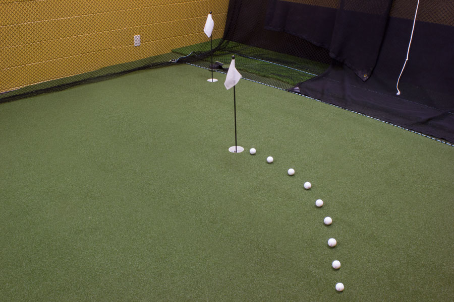 Golf balls lined behind a pin on an indoor putting green in PA